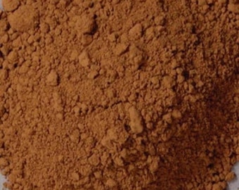 May include: A close-up of a pile of loose, brown powder. The powder is finely ground and has a slightly reddish hue.