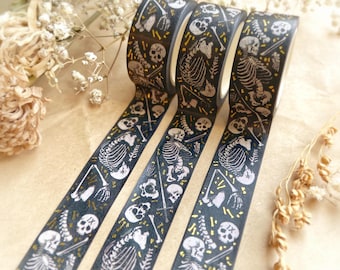 May include: Three rolls of black washi tape with a repeating pattern of white skeletons, skulls, and gold accents. The decorative tape is ideal for scrapbooking, crafting, and adding a spooky touch to projects.