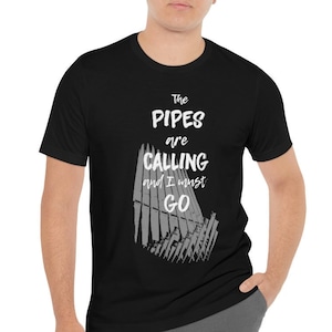 以下が含まれることがあります： パイプオルガンの白いグラフィックと「The Pipes are Calling and I must GO」というテキストが書かれた黒いTシャツ。