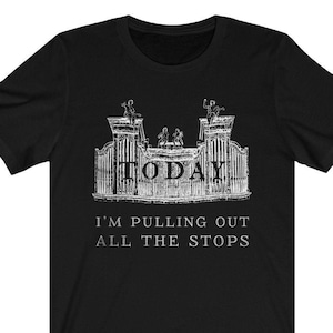 May include: Black t-shirt with a white graphic of a stylized organ and the text "TODAY I'M PULLING OUT ALL THE STOPS." The design features figures on top of the organ. A casual, unisex tee.