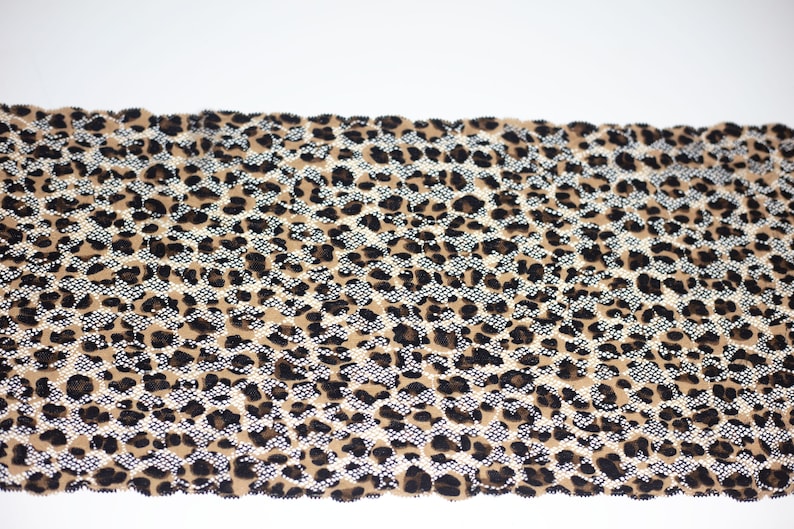 May include: A brown, black, and white leopard print fabric with a glittery finish.