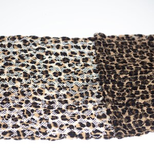 May include: A close-up of a brown and black leopard print fabric with a glittery finish. The fabric is folded in half, showing both sides.