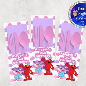 May include: Party favor sets featuring pink plastic cutlery, a purple napkin, and a decorative card with Elmo and Abby Cadabby from Sesame Street. The card reads "Alayjah's 2nd Birthday".