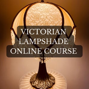 May include: A Victorian-style lampshade with a cream-colored, lace-patterned shade. The lampshade has a dark brown base with an ornate design and is adorned with hanging crystals. The text "VICTORIAN LAMPSHADE ONLINE COURSE" is displayed on the image.