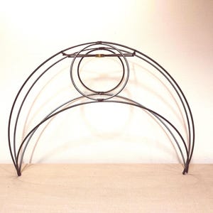 May include: A black metal headboard frame with a unique, arched design. The frame features a series of curved lines and circular accents, creating a modern and artistic aesthetic. The headboard is designed to fit a bed frame.