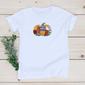 K&ouml;nnte beinhalten: Wei&szlig;es T-Shirt mit einem bunten Patchwork-K&uuml;rbis-Design.