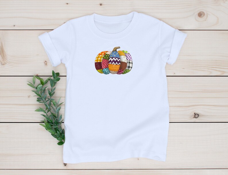 K&ouml;nnte beinhalten: Wei&szlig;es T-Shirt mit einem bunten Patchwork-K&uuml;rbis-Design.