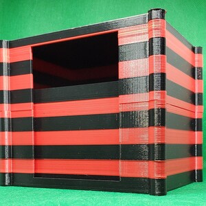 May include: A black and red striped storage box with a rectangular opening. The box is made of plastic and has a modern design.
