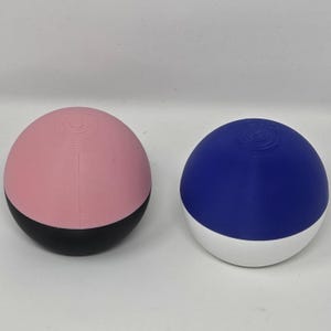 May include: Two spherical objects. One is pink with a black base, the other is blue with a white base. Both have a textured top.