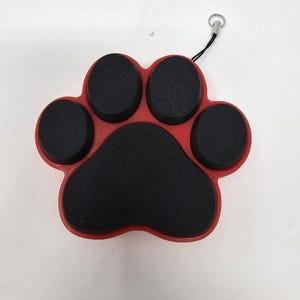 Puede incluir: Llavero con forma de huella de pata roja con almohadillas de pata de goma negra. El llavero tiene un lazo plateado para sujetarlo a una bolsa o cinturón.