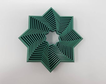 Puede incluir: Un juego de diez cortadores de galletas en forma de estrella verde, anidados uno dentro del otro, con el cortador más pequeño en el centro.