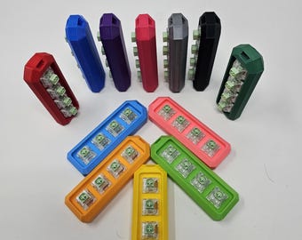 May include: A set of 12 colorful keycap holders, each with a different color and design. The holders are arranged in a circle, with a few in the center. The holders are made of plastic and have a smooth finish.