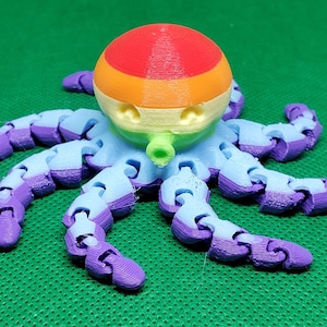 May include: A 3D printed octopus toy with a rainbow colored head and purple and blue tentacles. The octopus is made of plastic and has a segmented body.
