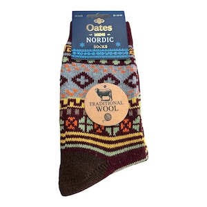 May include: A pair of knit socks featuring a multi-coloured Nordic pattern in shades of burgundy, yellow, light green, and grey. The packaging includes a blue header card labelled Oates Nordic Socks and a round tan tag with a sheep illustration.