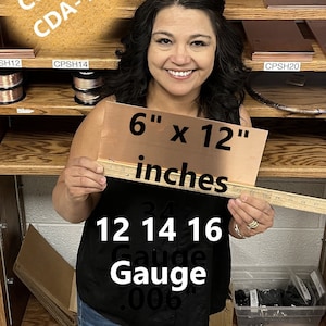 May include: A woman is holding a 6 by 12 inch sheet of copper, labelled "COPPER CDA-110", with a ruler showing the measurements and the text "12 14 16 Gauge .006".