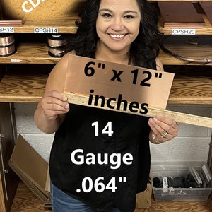 May include: A woman is holding a 6-inch by 12-inch sheet of copper. The copper sheet is 14 gauge and 0.064 inches thick. The text "COPPER CDA-110" is visible in the background.