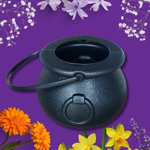 May include: A black plastic cauldron with a handle and a ring on the side. The cauldron is on a purple background.