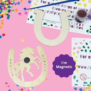 May include: Two wooden horseshoe shapes, one with a horse cutout, both with a magnetic backing. The horseshoe with the horse cutout is on a pink surface with colourful confetti. The other horseshoe is on a white card with the text "For our full range of party favours visit www.craftycrocbox.e".