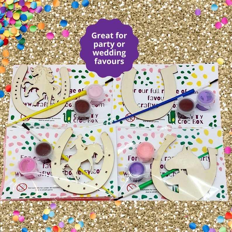 May include: Four wooden horseshoe craft kits with paint pots and brushes. Each horseshoe has a different horse design. The text on the packaging reads "Great for party or wedding favours" and "www.craftycrocbox.com".