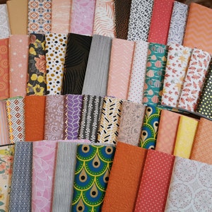 Peut inclure: Une collection de carnets avec des couvertures à motifs variés. Les motifs comprennent des motifs floraux, géométriques et abstraits dans des couleurs comme l'orange, le rose, le noir et l'or. Les carnets sont empilés, présentant une variété de styles.