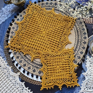 Puede incluir: Dos doilies de ganchillo en color amarillo mostaza. Los doilies están sobre una superficie con estampado en blanco y negro. El texto "CROCHET PATTERN PHOTO TUTORIAL" está en el lado izquierdo de la imagen. El texto "ENGLISH RUSSIAN" está en la parte inferior izquierda de la imagen.
