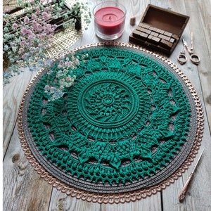 Könnte beinhalten: Detaillierte Aufnahme einer grünen gehäkelten Tischdecke mit floralem Design, platziert auf einem dekorativen Platzset. Das Bild enthält den Text "CROCHET PATTERN PHOTO TUTORIAL" und "ENGLISH RUSSIAN". Eine brennende rote Kerze und eine Schere sind ebenfalls zu sehen.