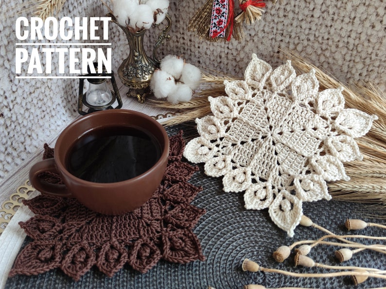 K&ouml;nnte beinhalten: Zwei geh&auml;kelte Untersetzer, einer braun und einer beige, mit einer Tasse Kaffee auf dem braunen Untersetzer. Die Untersetzer befinden sich auf einer grauen, strukturierten Oberfl&auml;che. Der Text "CROCHET PATTERN" befindet sich in der oberen linken Ecke des Bildes.