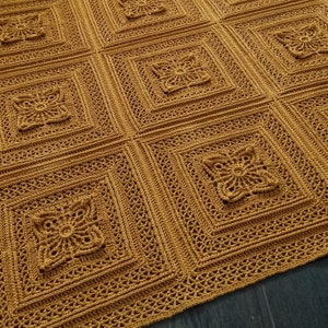 May include: A mustard yellow crochet blanket featuring a repeating pattern of square motifs. Each square consists of a central floral-like design surrounded by concentric geometric borders with intricate openwork stitching throughout.