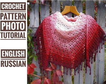 May include: A crocheted shawl with a gradient of red, pink, and white. The shawl is hanging on a wooden hanger against a wooden fence. The text "CROCHET PATTERN PHOTO TUTORIAL ENGLISH RUSSIAN" is visible in the image.
