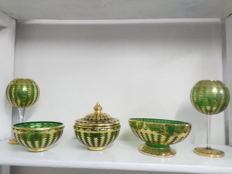 Puede incluir: Conjunto de cuatro cuencos y jarrones de vidrio verde y dorado con intrincados patrones. Los cuencos y jarrones est&aacute;n decorados con un patr&oacute;n repetitivo de hojas doradas sobre un fondo verde.