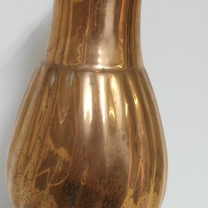 Op de afbeelding: Een vintage koperen vaas met een bolvormig lichaam en een gegroefd ontwerp. De vaas heeft een voetstuk en een smalle hals. Het koper heeft een warme, verouderde patina met wat verkleuring.