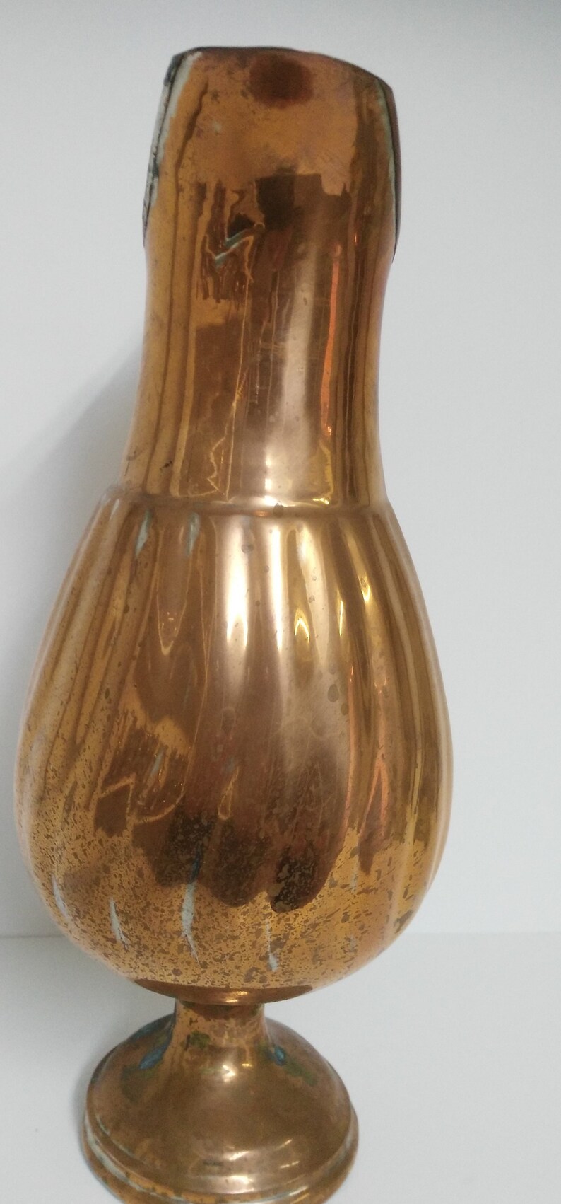 Op de afbeelding: Een vintage koperen vaas met een bolvormig lichaam en een gegroefd ontwerp. De vaas heeft een voetstuk en een smalle hals. Het koper heeft een warme, verouderde patina met wat verkleuring.