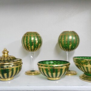 Puede incluir: Conjunto de cinco cuencos y copas de vidrio verde y dorado con un patr&oacute;n decorativo. Los cuencos y las copas son todos del mismo estilo, con una base verde y detalles dorados.