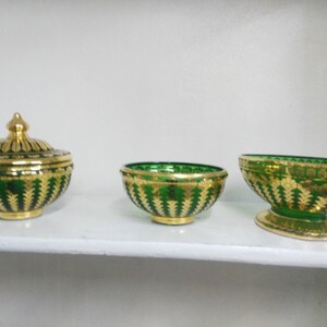 Puede incluir: Tres cuencos decorativos con dise&ntilde;os de mosaico dorado y verde. Los cuencos est&aacute;n en un estante blanco. El cuenco de la izquierda tiene una tapa.