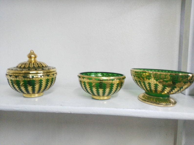 Puede incluir: Tres cuencos decorativos con dise&ntilde;os de mosaico dorado y verde. Los cuencos est&aacute;n en un estante blanco. El cuenco de la izquierda tiene una tapa.