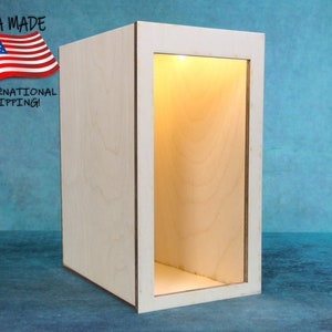 Peut inclure: Une vitrine en bois avec une lumière à l'intérieur. La vitrine est en bois clair et a une façade transparente. La vitrine est éclairée de l'intérieur, créant une lueur chaleureuse.