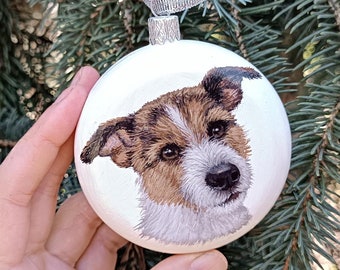 May include: White Christmas ornament with a hand-painted portrait of a brown and white dog. The dog has a black nose and brown eyes.