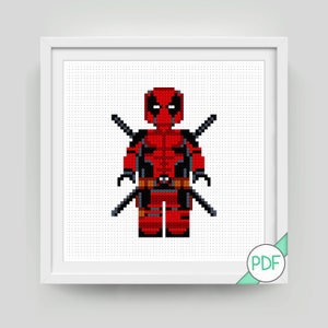 Könnte beinhalten: Ein gerahmtes Kreuzstichbild von Deadpool in seinem charakteristischen rot-schwarzen Anzug, komplett mit Schwertern. Das pixelige Design ist vor einem weißen Hintergrund platziert und in einem weißen quadratischen Rahmen eingefasst. Ein PDF-Symbol befindet sich in der unteren rechten Ecke.