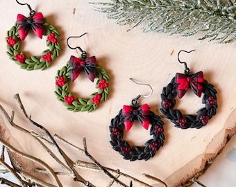 May include: Three pairs of Christmas wreath earrings. Each pair features a green, red, and black wreath with a red bow. The wreaths are made of polymer clay.