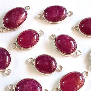 May include: Ten oval-shaped gemstone beads with silver connectors. The beads are a deep, rich burgundy color.