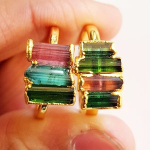 May include: Two gold rings with stacked multi-colored tourmaline gemstones. The rings feature a mix of pink, green, and blue gemstones.