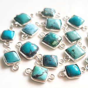 May include: A collection of turquoise gemstone connector charms with silver-toned metal settings. The charms are square-shaped and have two loops for attaching to jewelry.