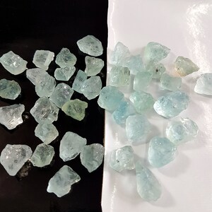 Puede incluir: Una colecci&oacute;n de piedras brutas de aguamarina azul claro. Las piedras son de varios tama&ntilde;os y formas, y algunas tienen un ligero tono verde.
