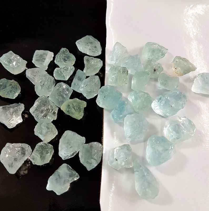 Puede incluir: Una colecci&oacute;n de piedras brutas de aguamarina azul claro. Las piedras son de varios tama&ntilde;os y formas, y algunas tienen un ligero tono verde.