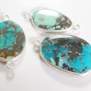 May include: Three oval turquoise gemstone pendants with silver bezels and jump rings. The turquoise stones have a mottled blue and brown pattern.
