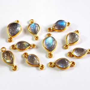 May include: A collection of teardrop-shaped labradorite gemstone pendants with gold-colored metal settings. Each pendant has a loop at the top and bottom for attaching to a chain or other jewelry component. The gemstones display iridescent blue and gray hues.