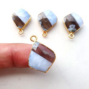 Könnte beinhalten: Drei vergoldete Anhänger mit einem hellblauen und braunen Achat-Edelstein. Die Anhänger haben die Form eines Diamanten und eine Öse oben zum Anbringen an eine Halskette oder ein Armband.