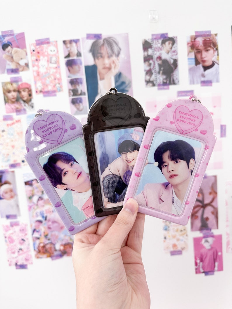 May include: Three K-pop idol photo card holders in purple, black, and pink. Each holder has a heart-shaped top with the text "EMOTIONAL SUPPORT KPOP IDOL." The holders contain photos of K-pop idols.