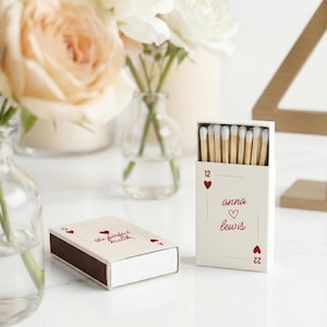 May include: Two matchboxes, one closed and one open, with white matchsticks. The closed box reads "the perfect match" and the open box has the names "anna lewis" and a heart symbol. The boxes have red heart suit symbols.