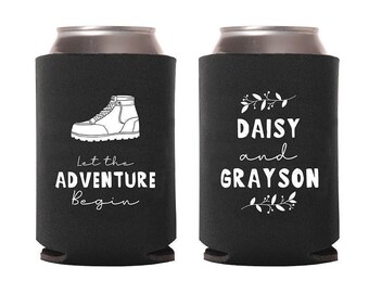 May include: Two black can coolers. One features a white illustration of a hiking boot with the text "Let the Adventure Begin". The other has the names "Daisy and Grayson" with floral accents.